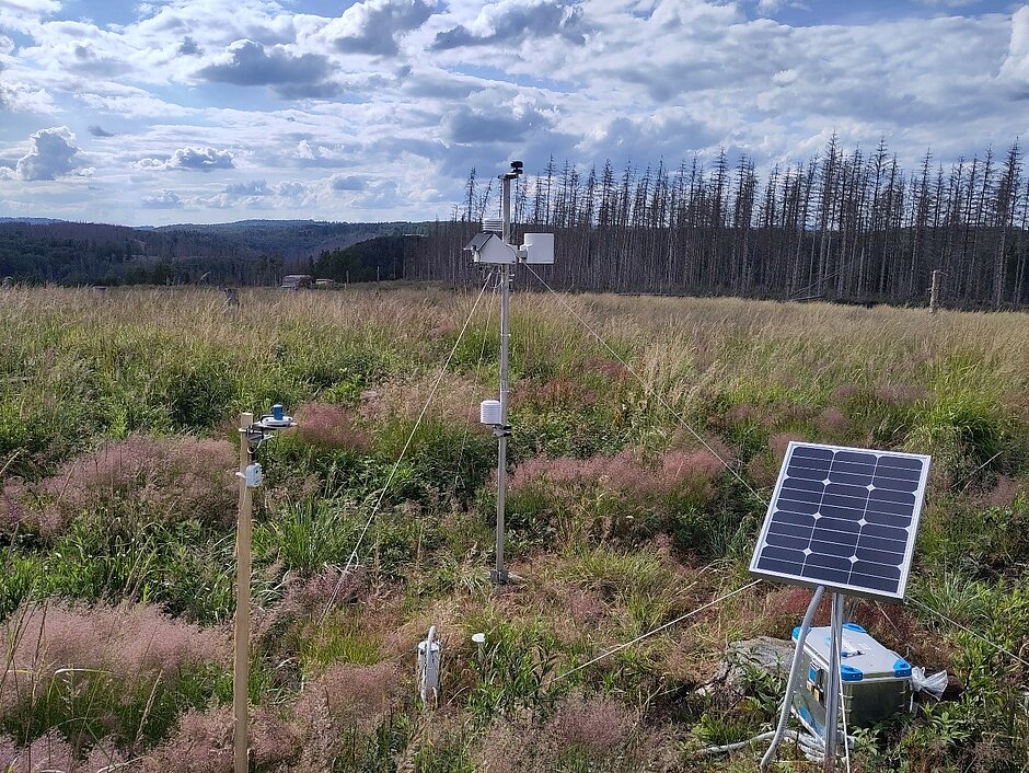 Klimastation mit Solarpanel und weiteren Messgeräten auf einer Freifläche.